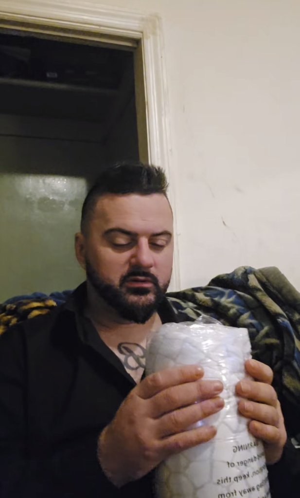 MC Aldin drži zapakiranu bijelu posteljinu iz poklon-paketa